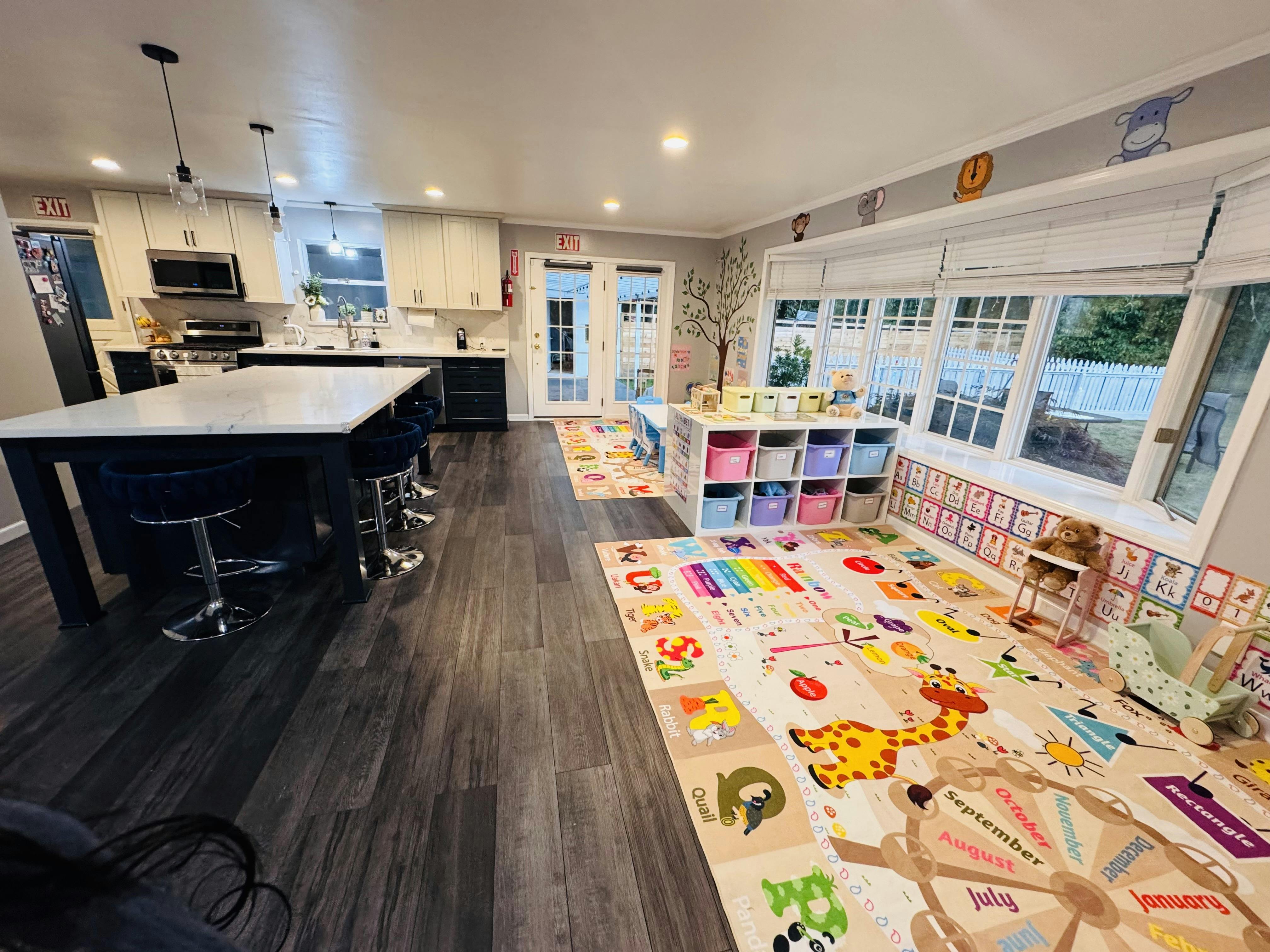 kitchen area with white cabinets and a large island, next to a playroom with colorful mats