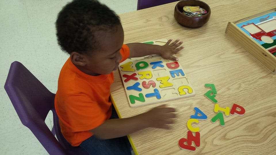 Child playing with an alphabet puzzle at a table