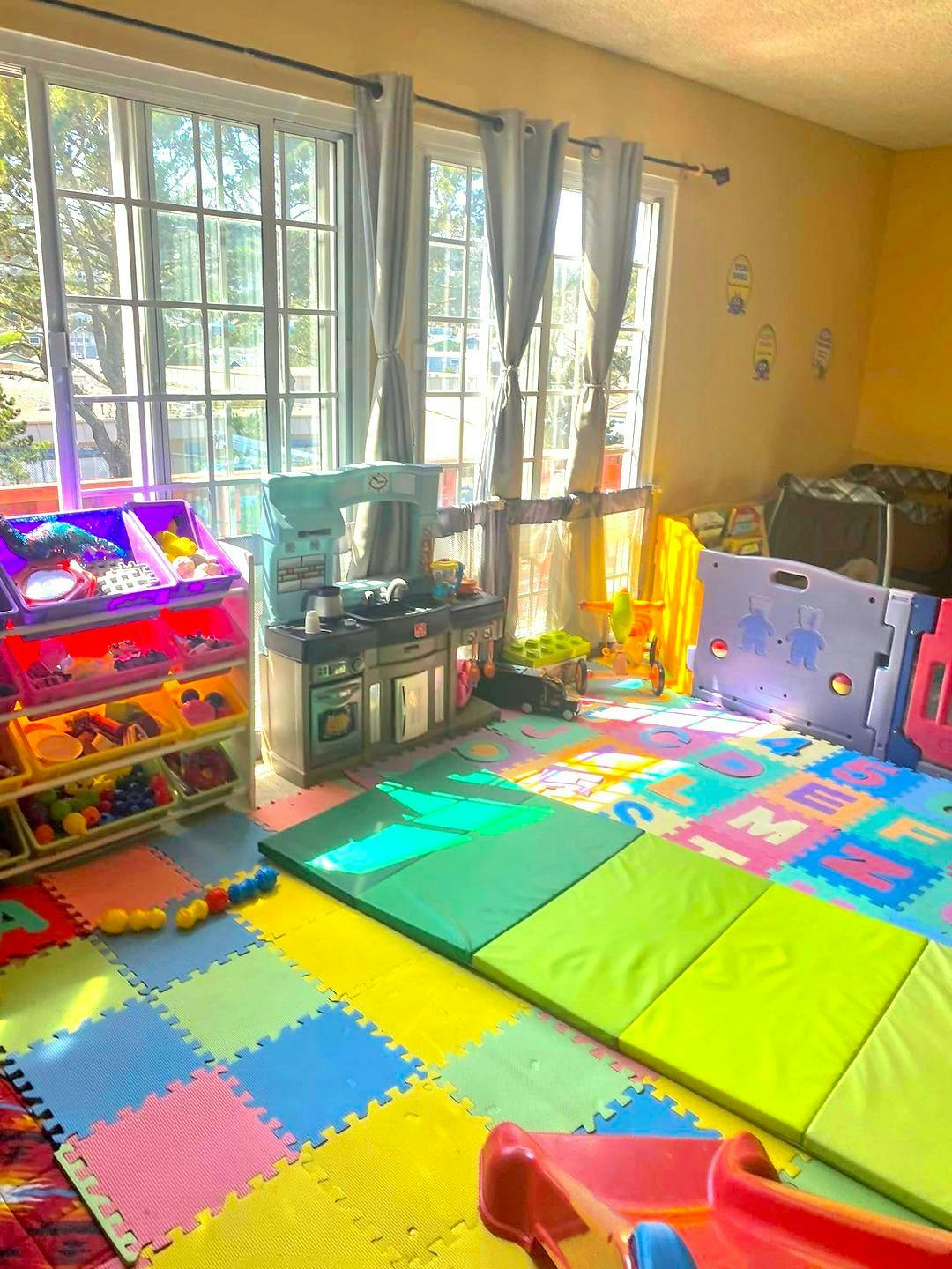 Playroom with colorful floor mats, toy kitchen, and storage shelves