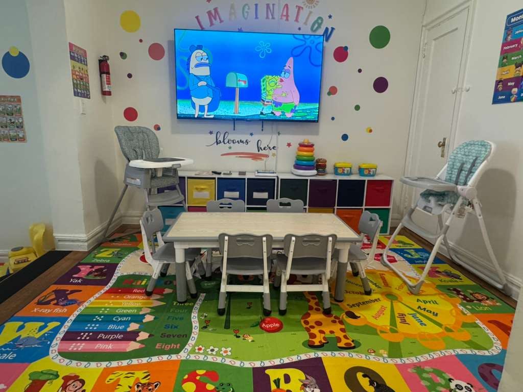 Children's play area with a colorful rug, small table and chairs, and a TV