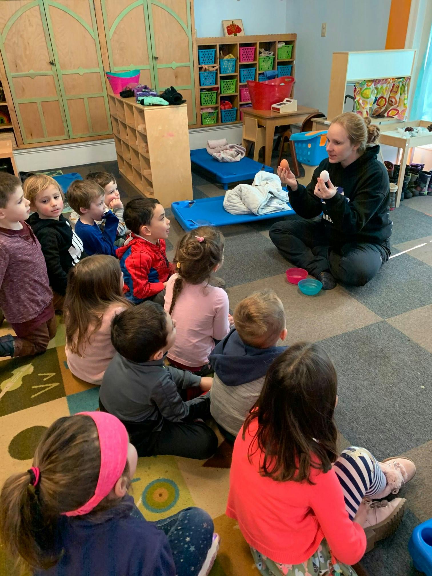 Person sitting on floor with children in a classroom