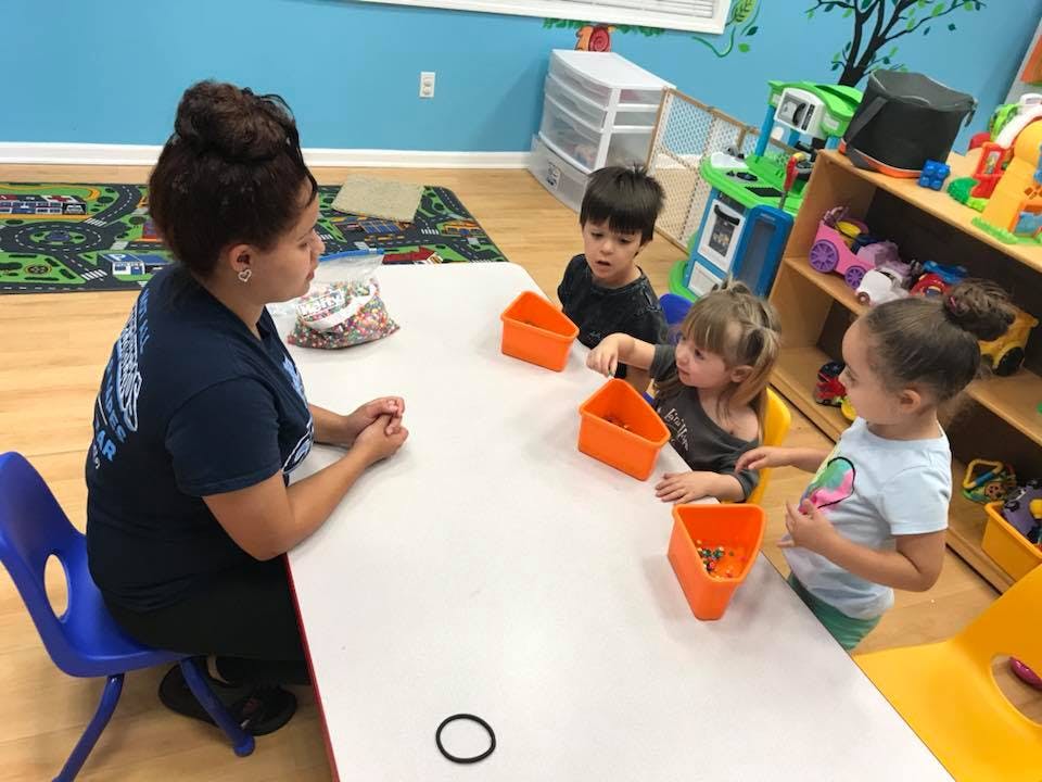 Person and three children sitting at a table with orange containers
