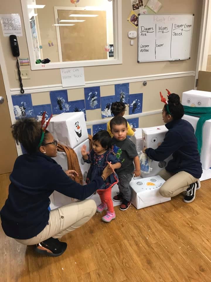 Two adults and three children playing with snowman decorations in a room