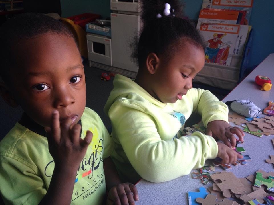 Two children playing with puzzles at a table