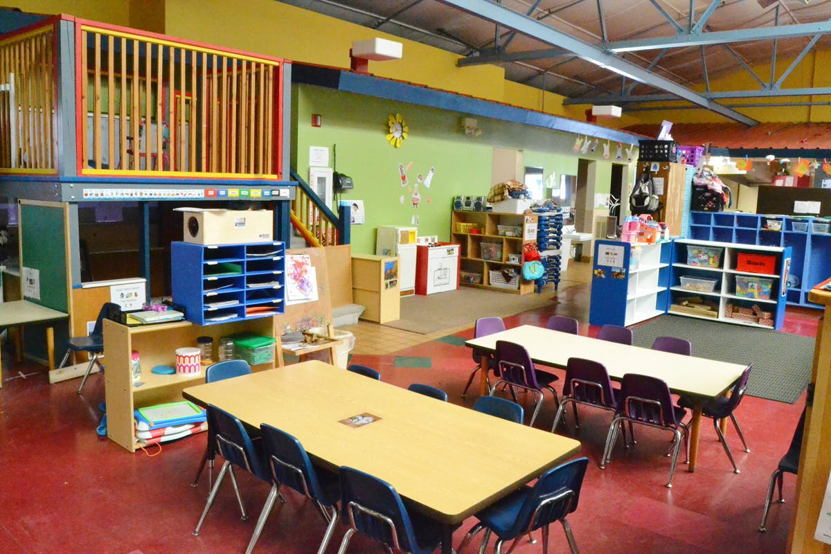 Classroom with tables and chairs, play structure, and storage shelves