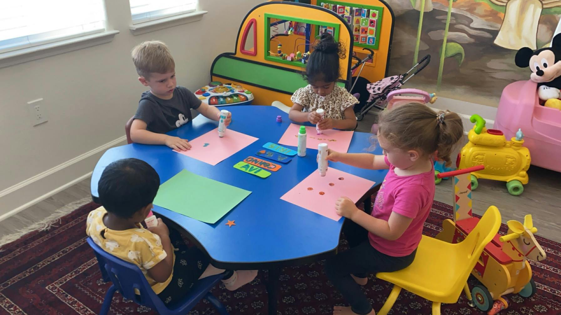 Four children sitting at a table doing crafts
