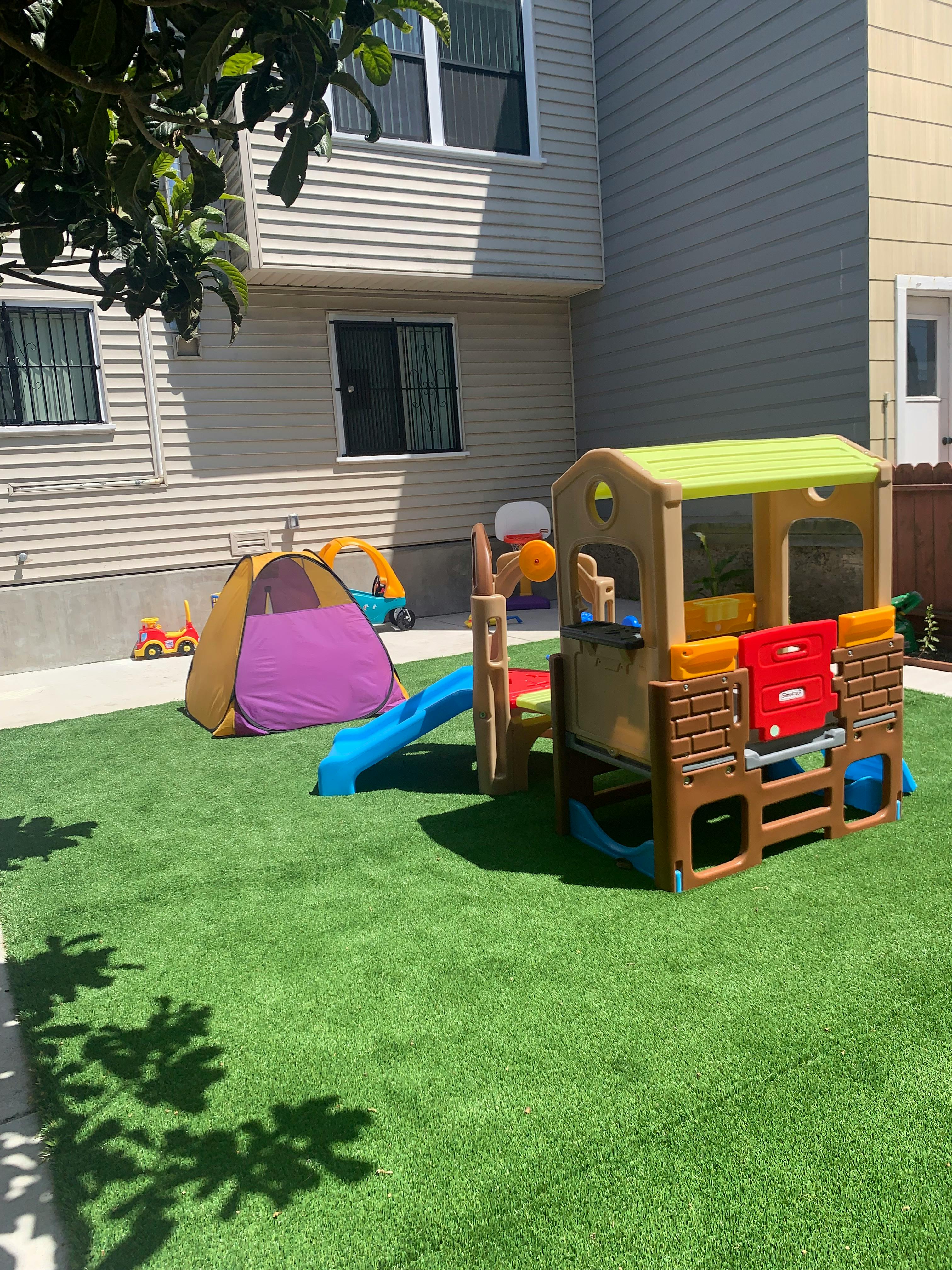 Play structure with slide and tent on artificial grass