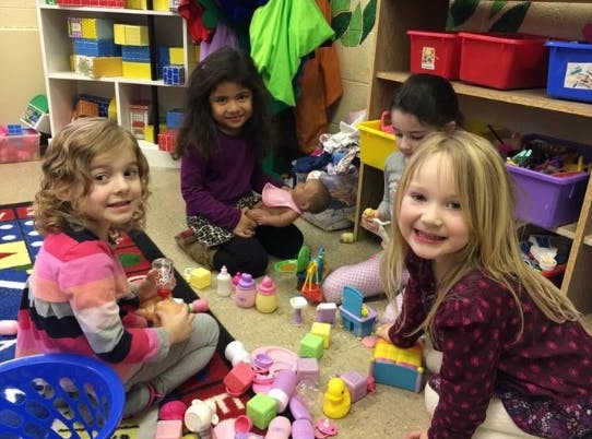 Four children playing with toys on the floor