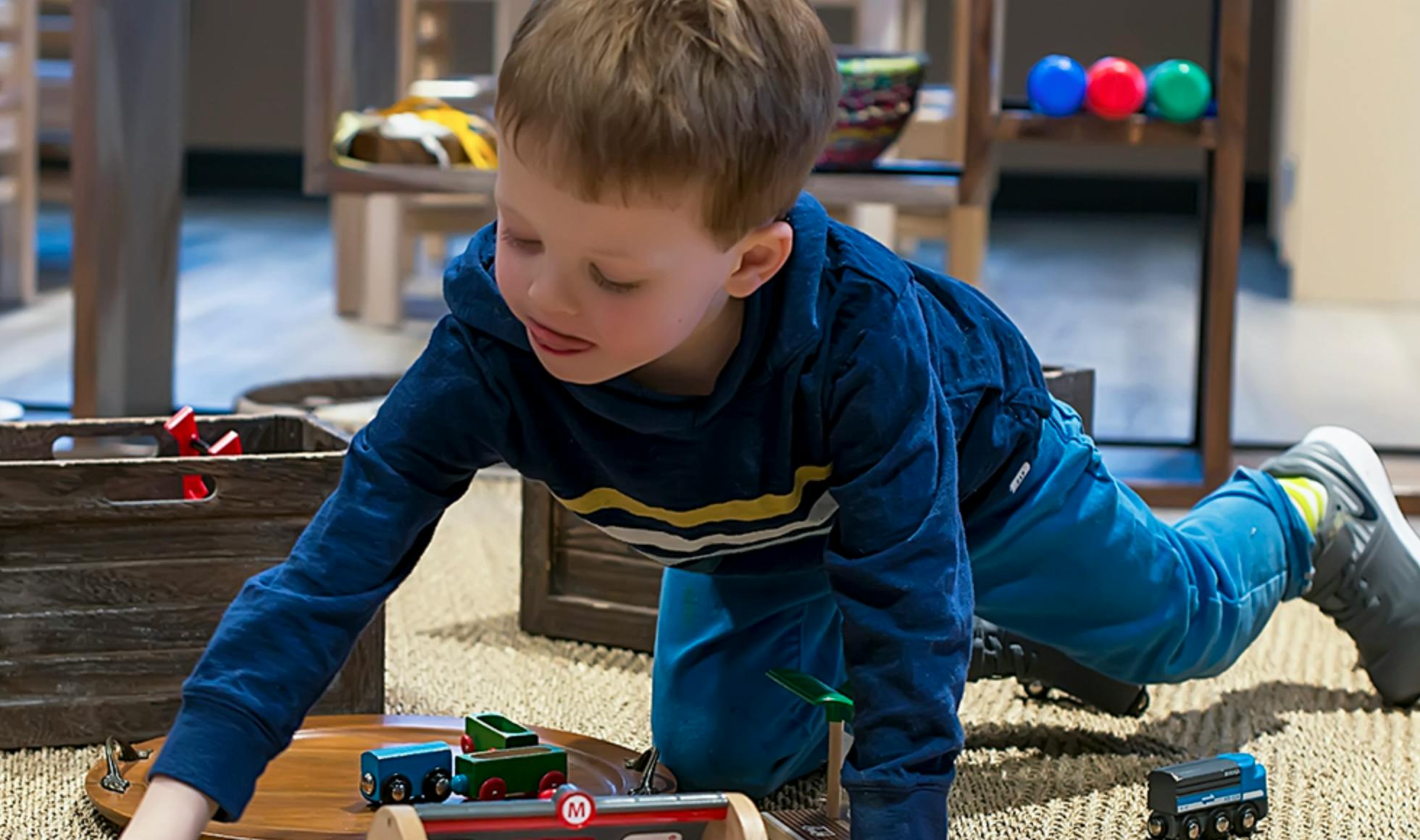 Child playing with toy trains on the floor