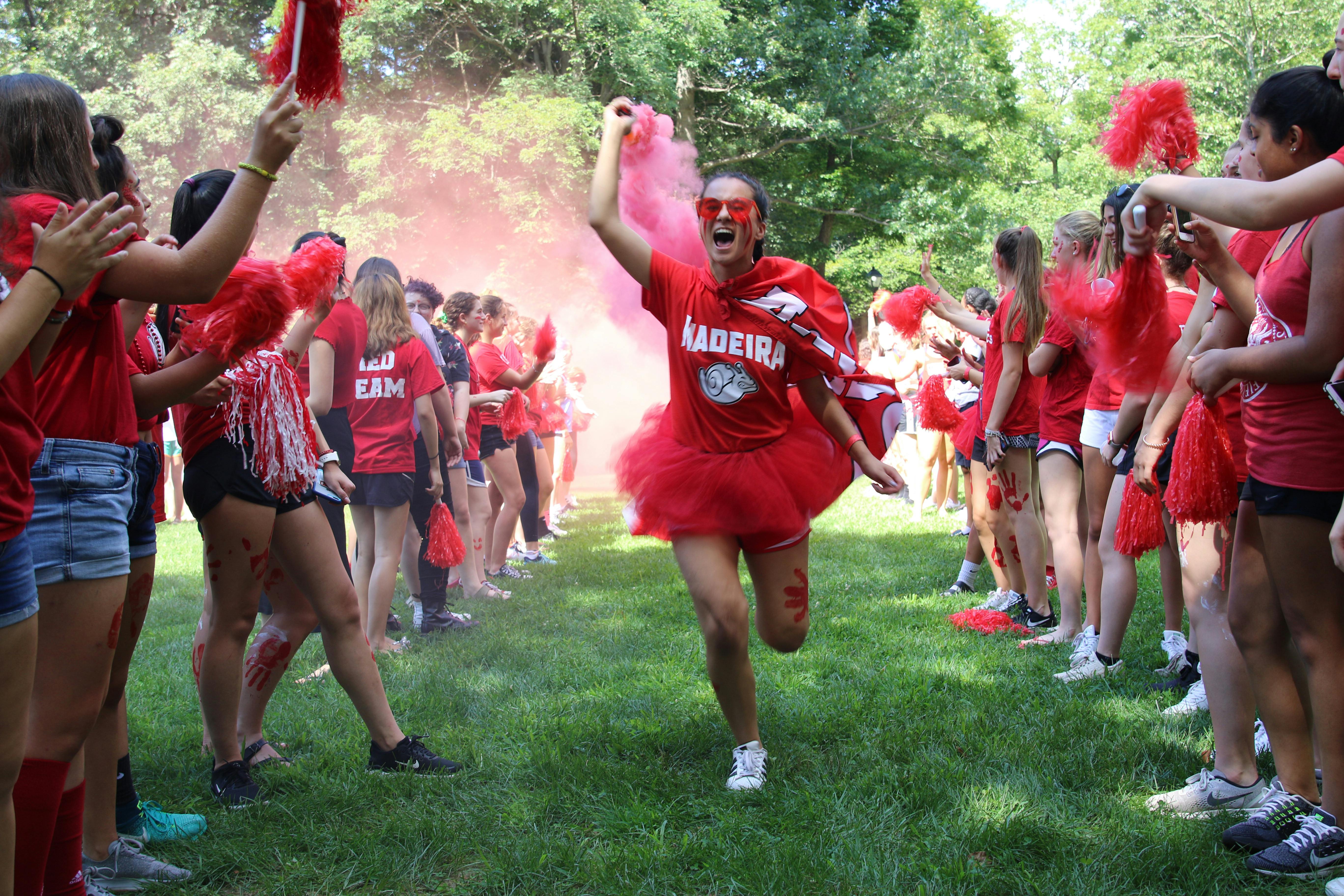Person in red running through a line of people with red smoke