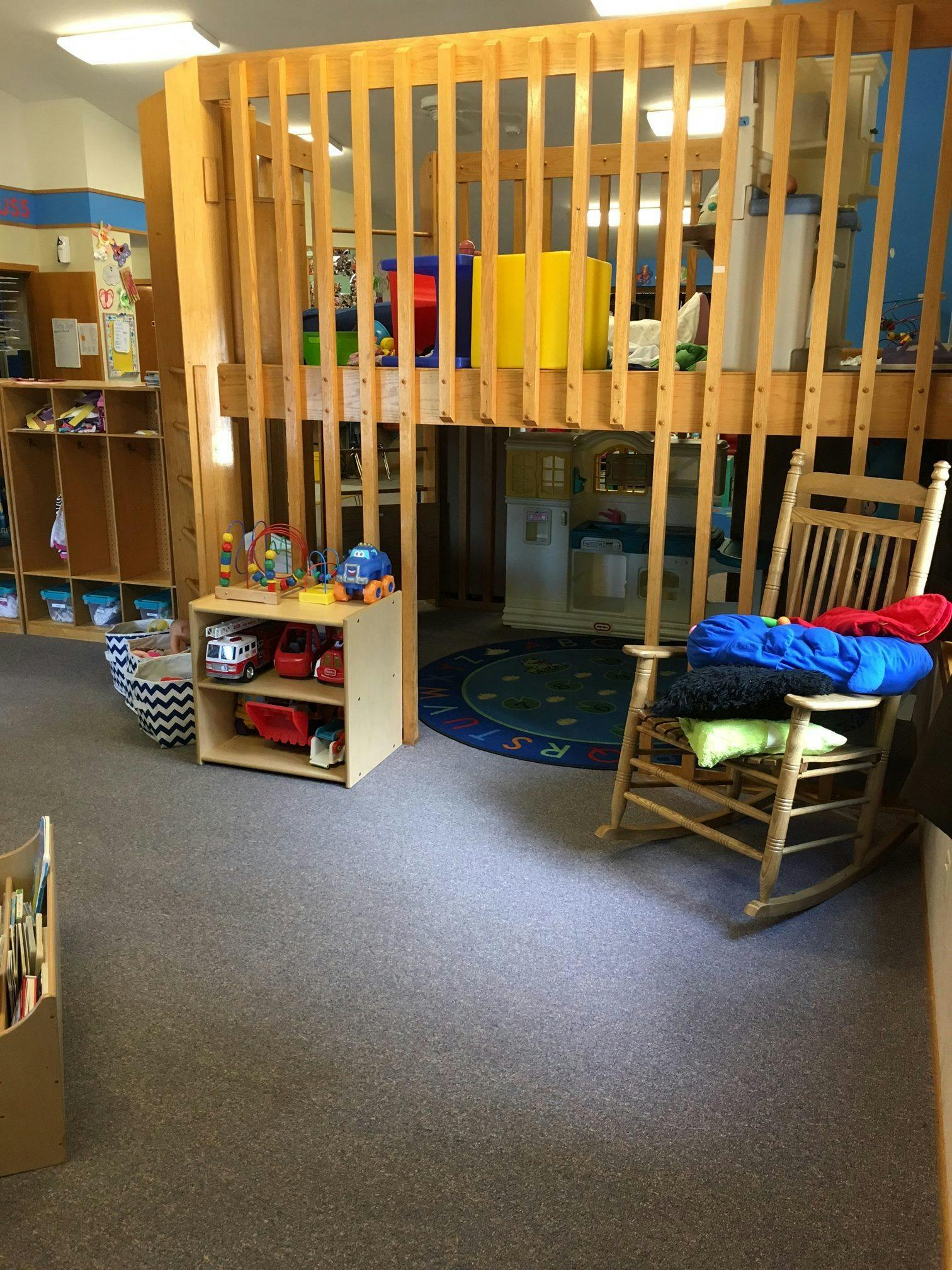 Indoor play area with a wooden loft structure and a rocking chair