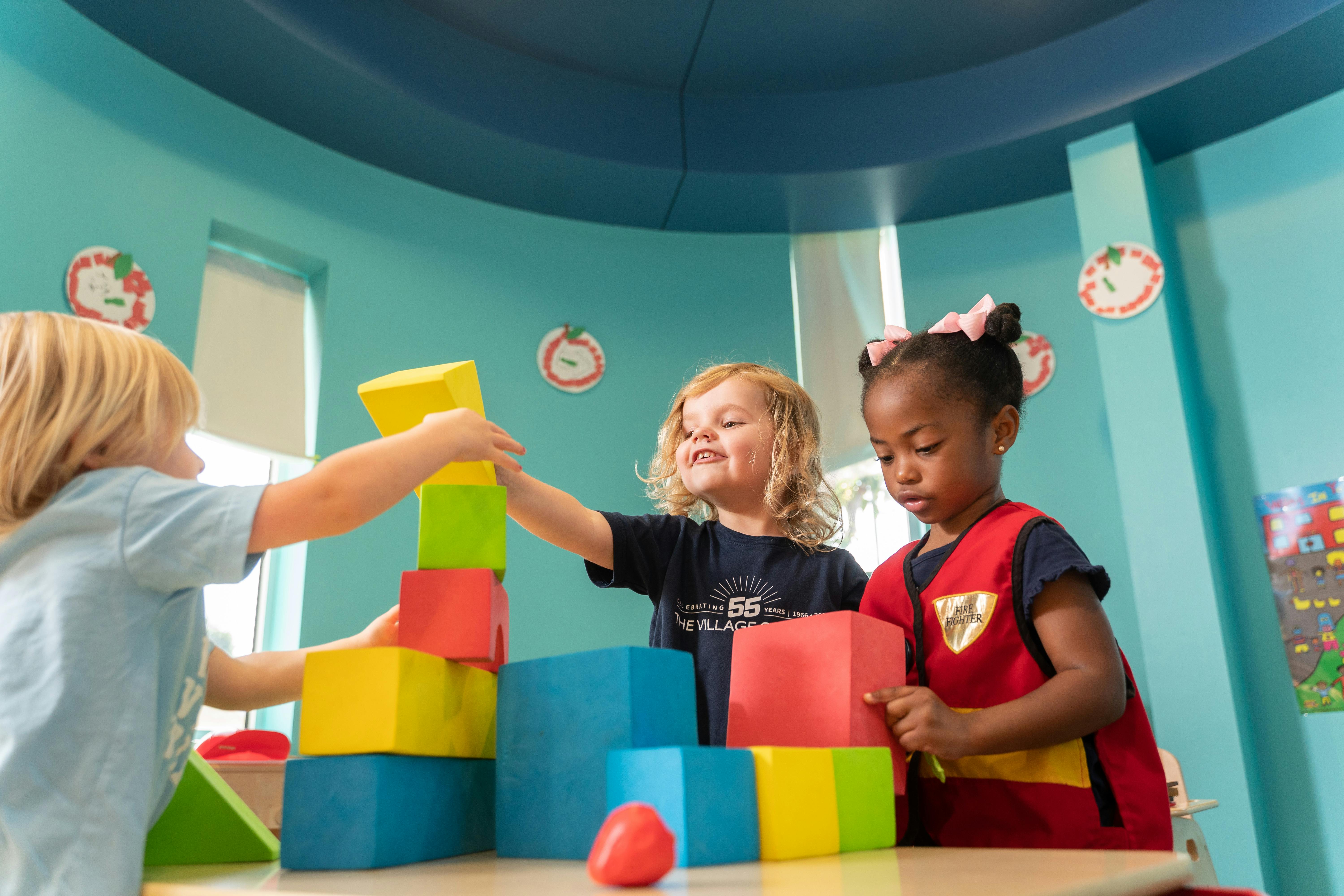 Three children playing with colorful building blocks