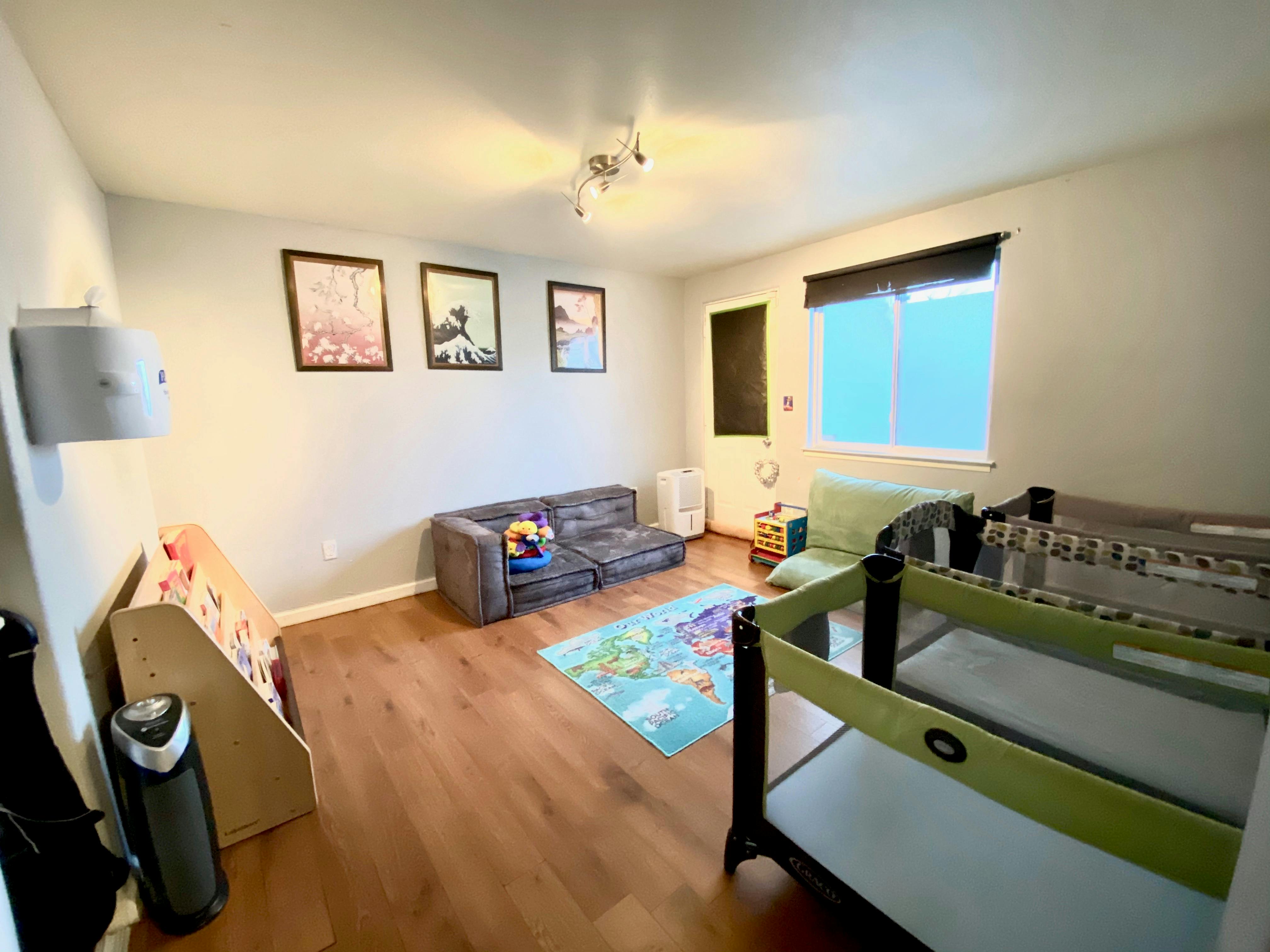 Living room with a gray sofa, blue rug, and two cribs