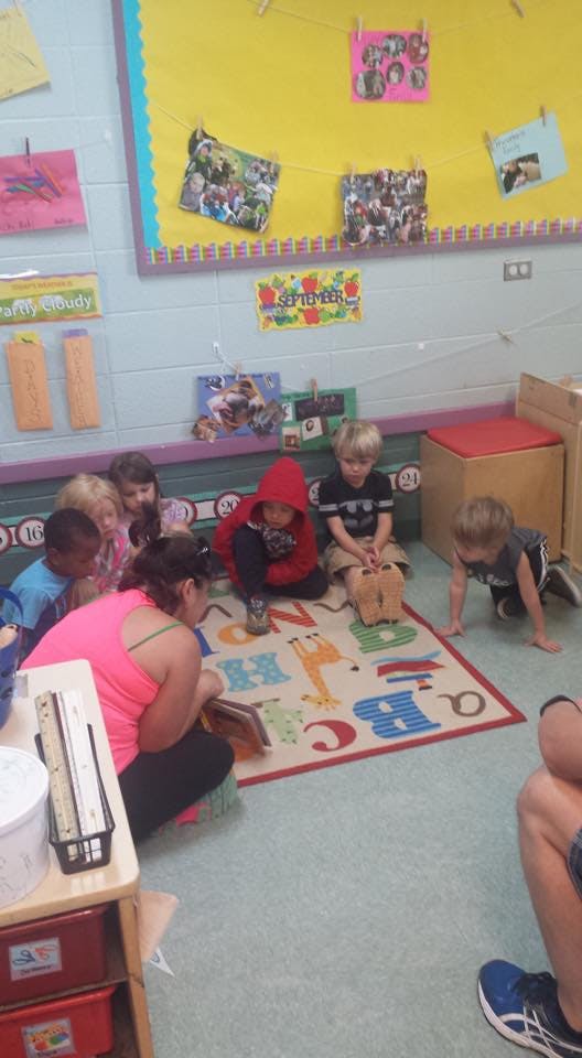 Adult and children sitting on a rug in a classroom