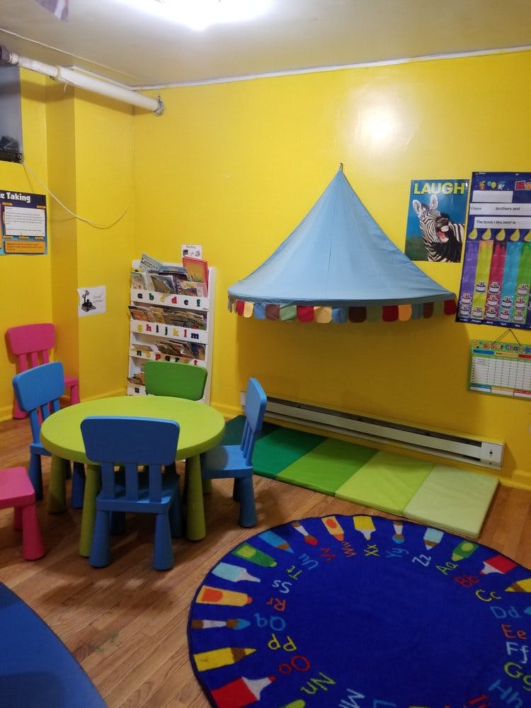 Children's classroom with small table and chairs, play tent, and alphabet rug