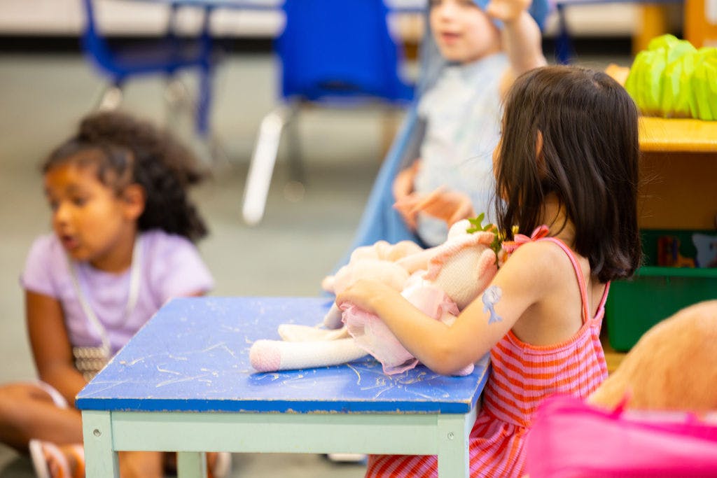 Child playing with a doll at a small table