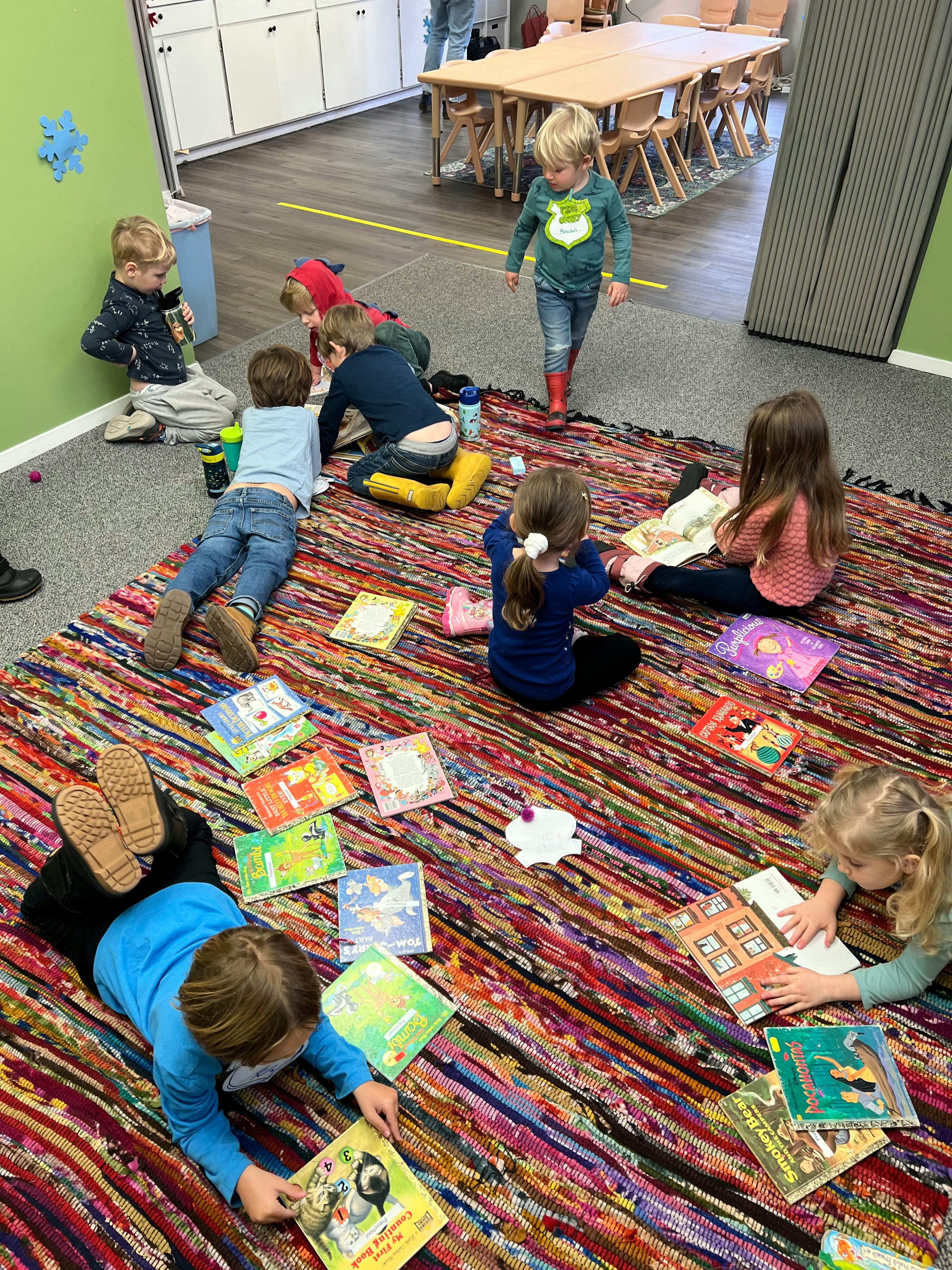 Children reading books on a colorful rug in a classroom