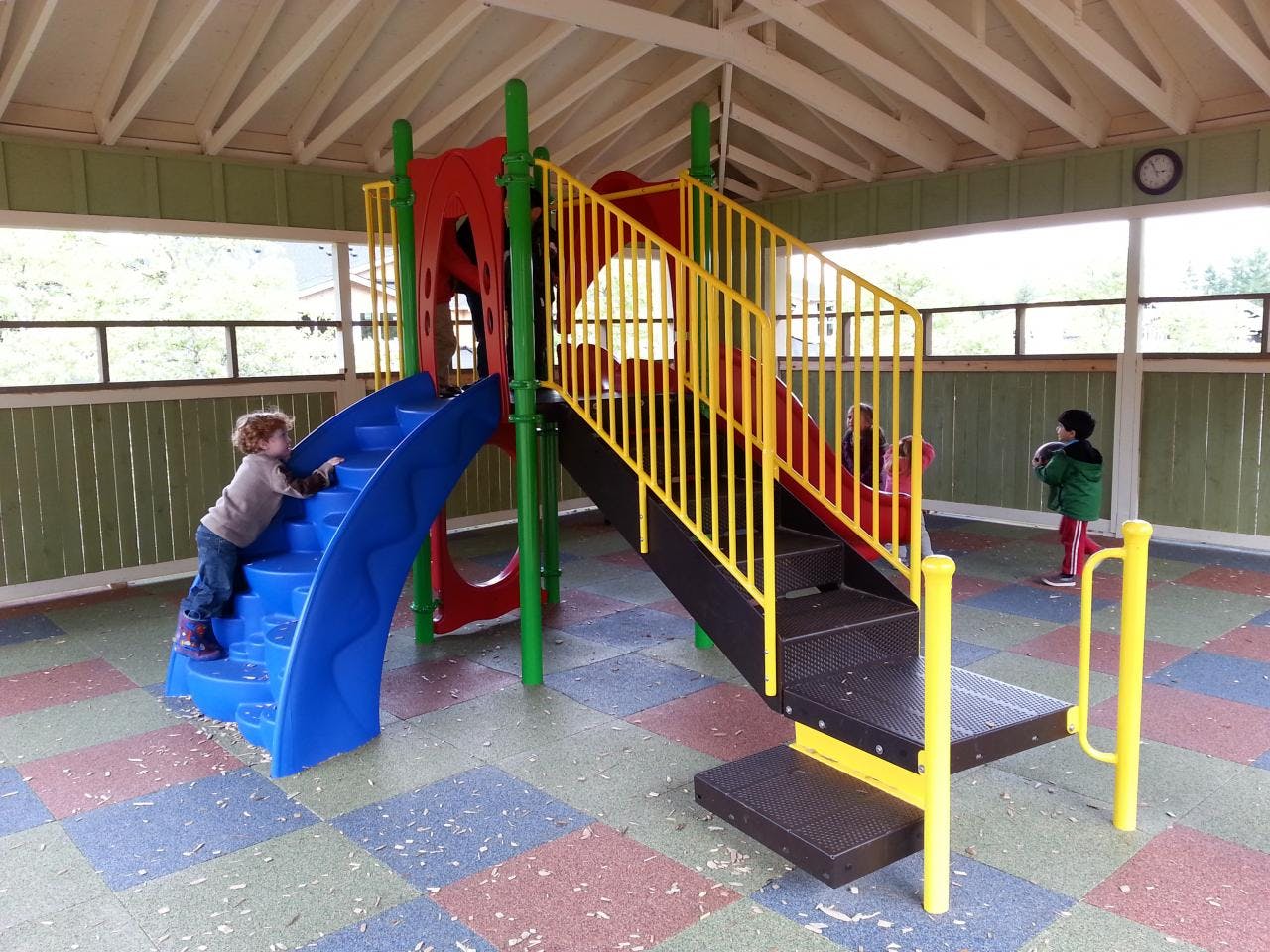 Child climbing steps of a blue slide on a playground