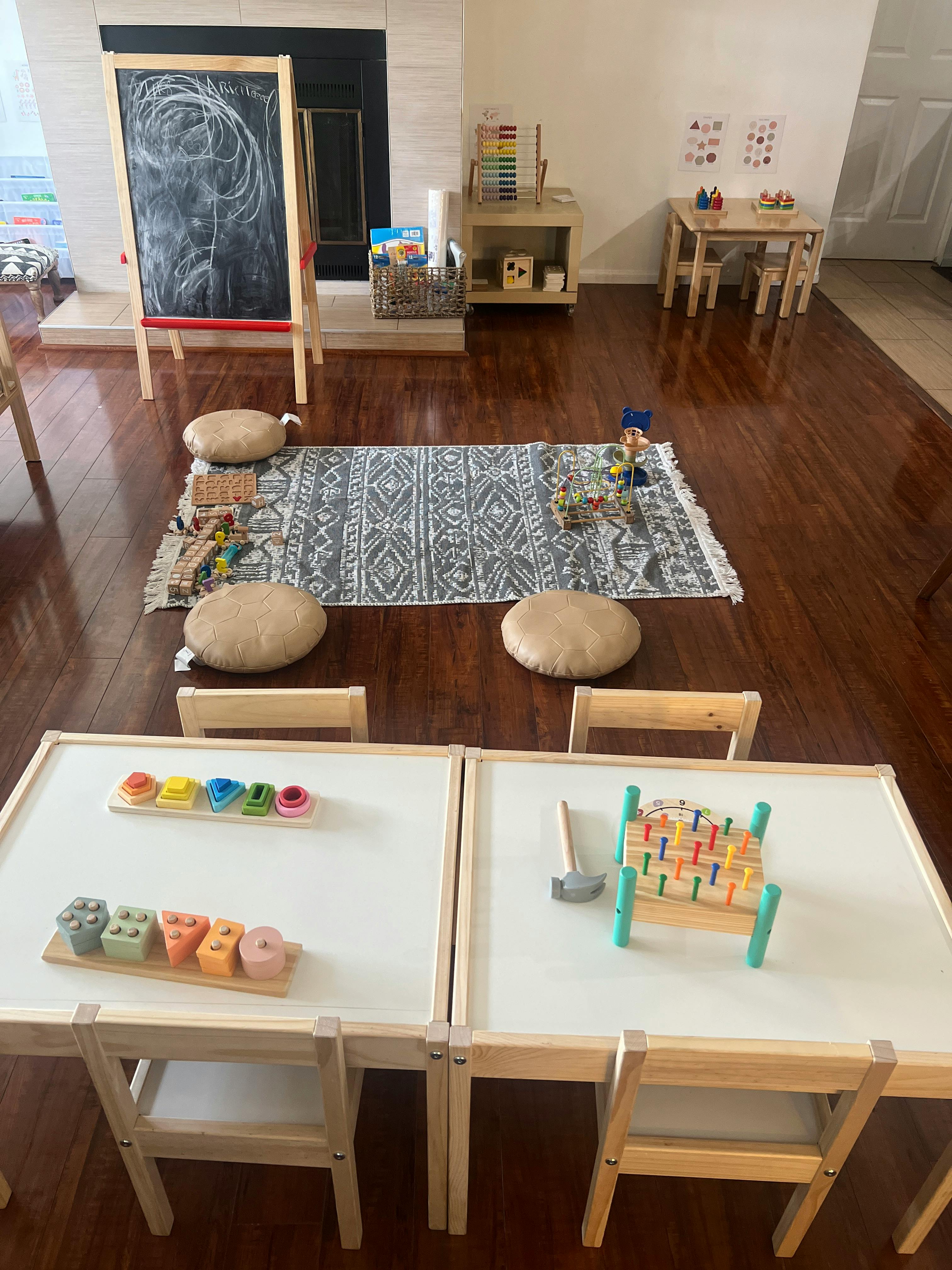 Children's play area with small tables, chairs, and a chalkboard