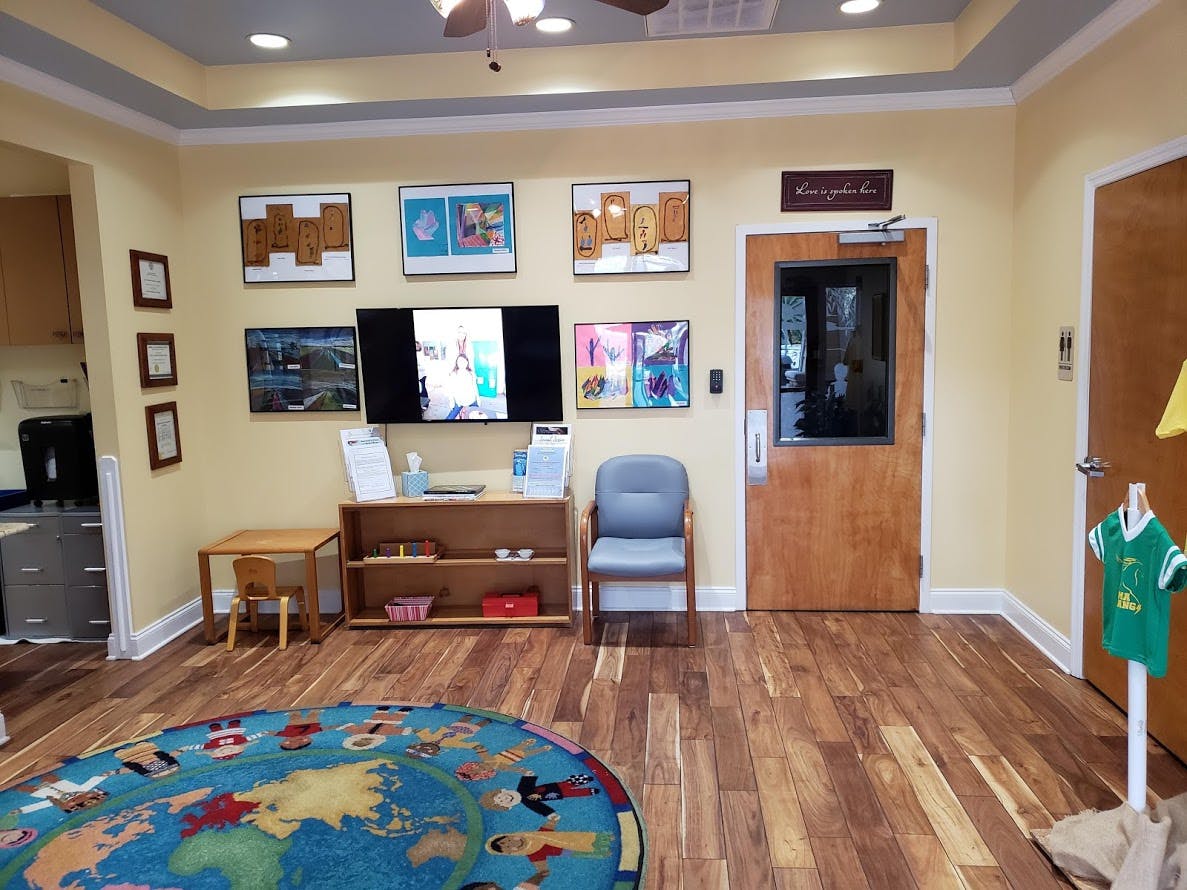 Room with wood floor, colorful rug, small table, chair, and television