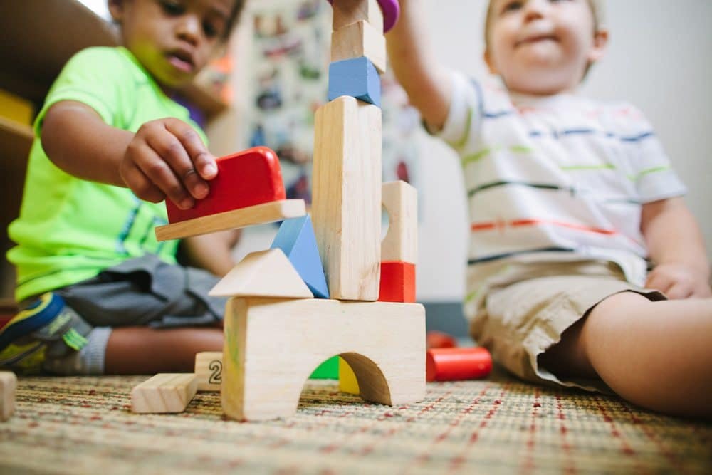 Two children playing with wooden building blocks