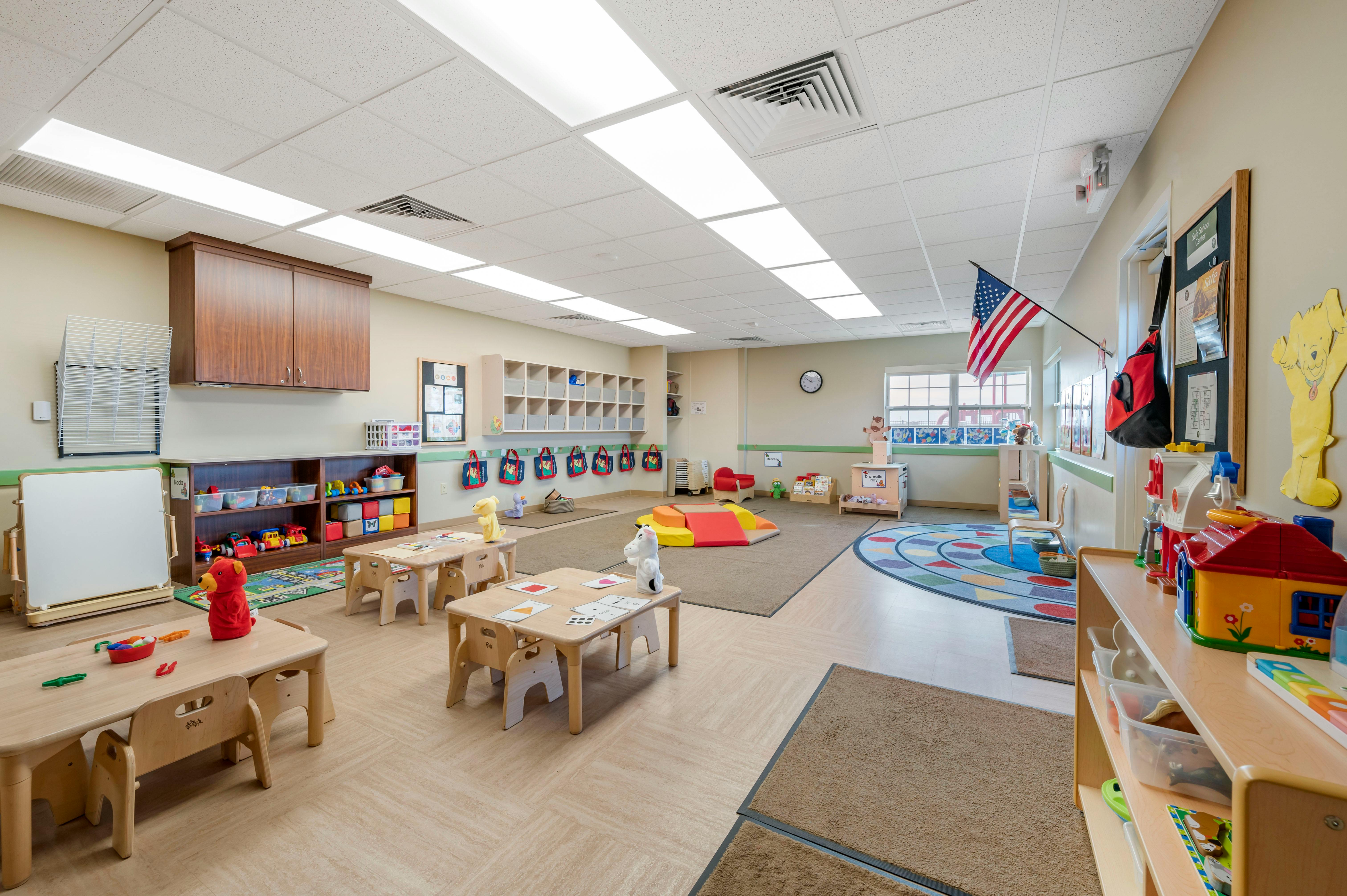 Empty colorful children's classroom with small tables, chairs, and toys