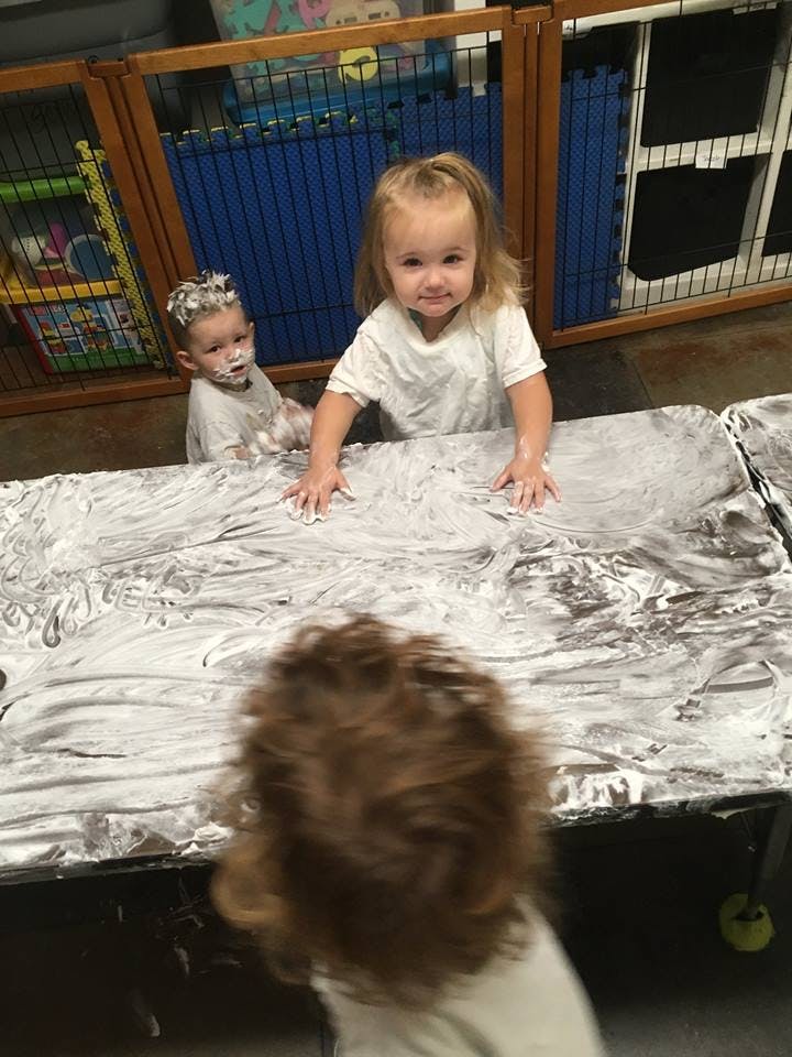 Two children playing with white foam on a table