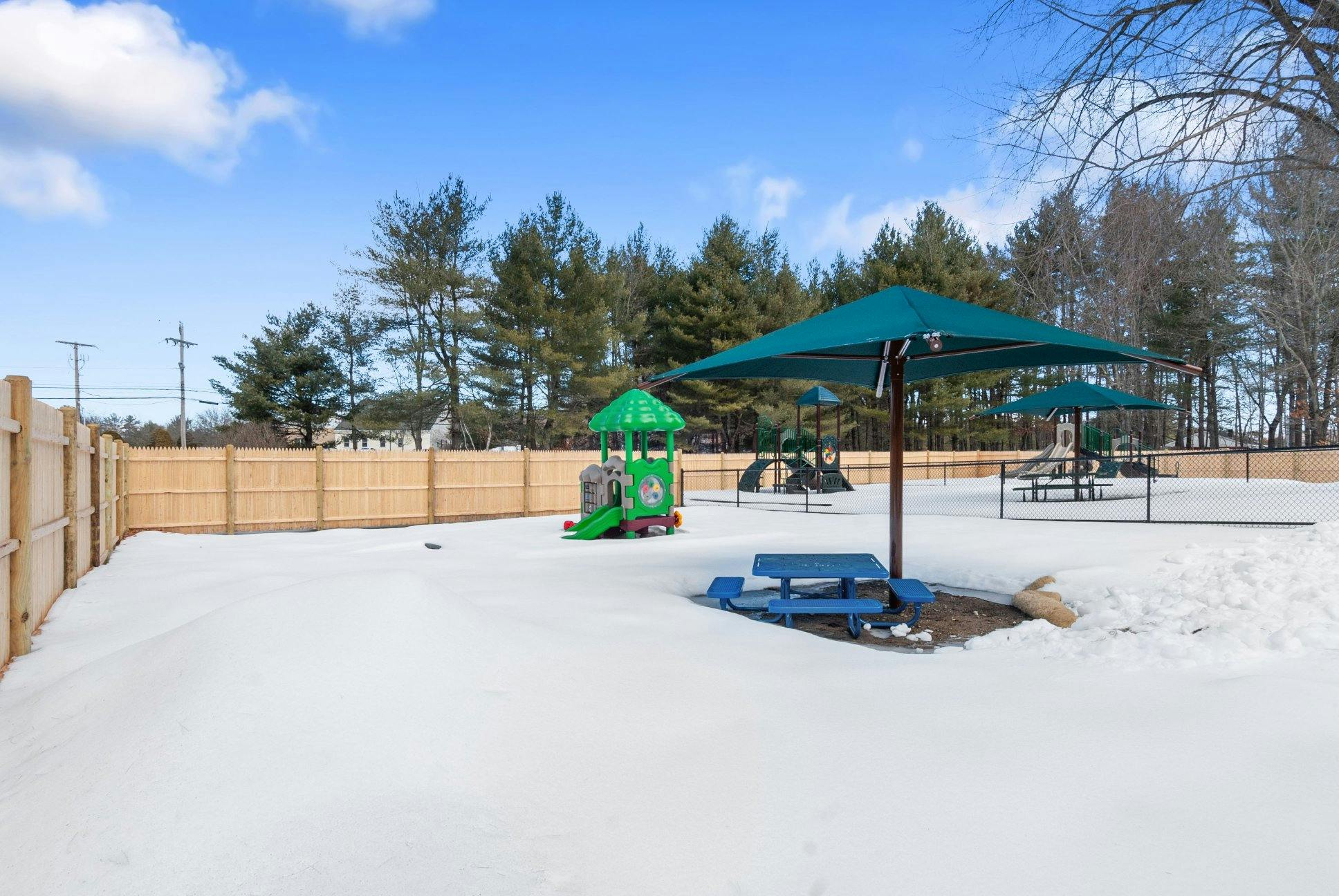 Snowy playground with colorful equipment and picnic table