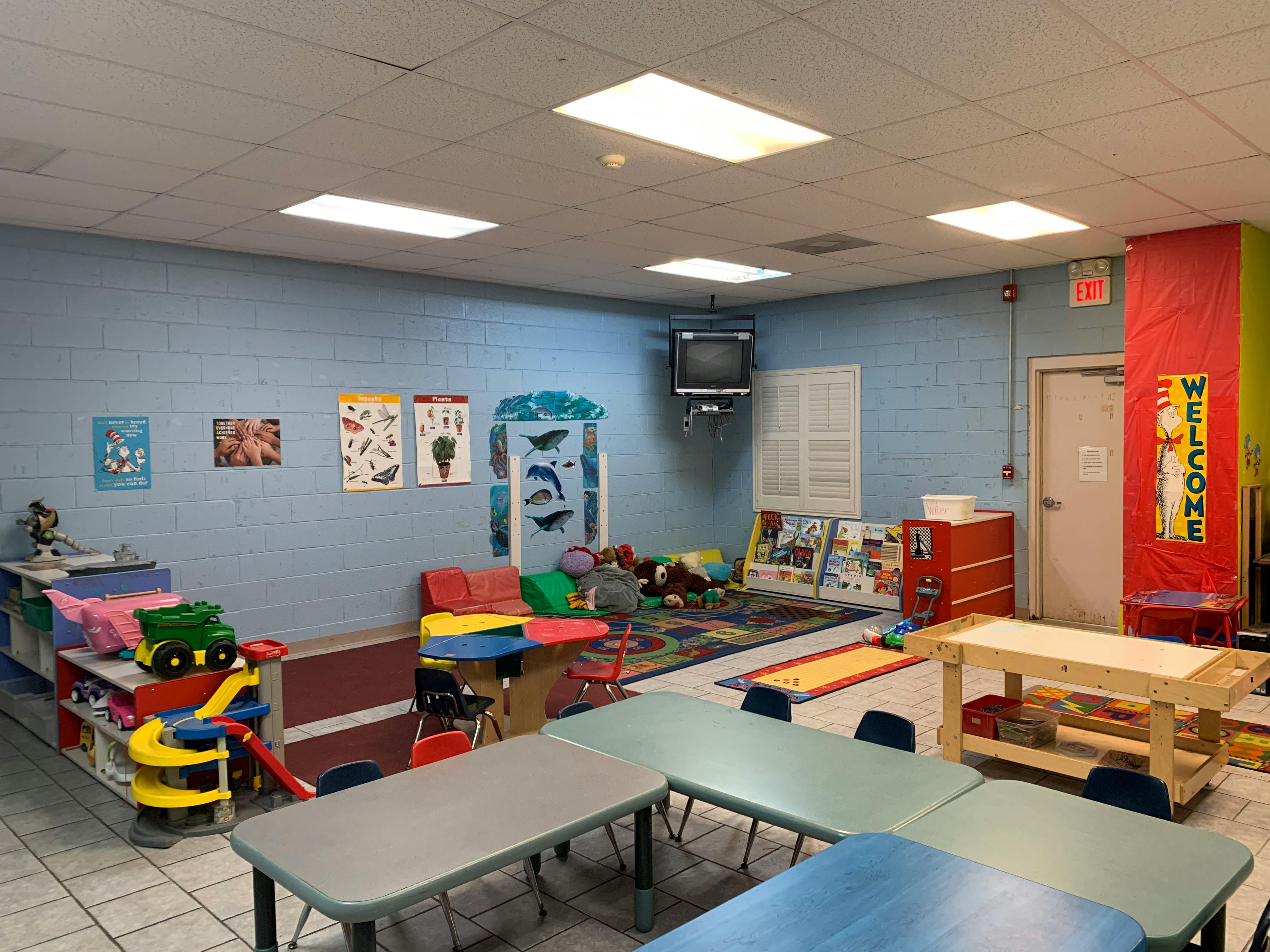 Classroom with blue block walls, colorful tables and chairs, and play areas