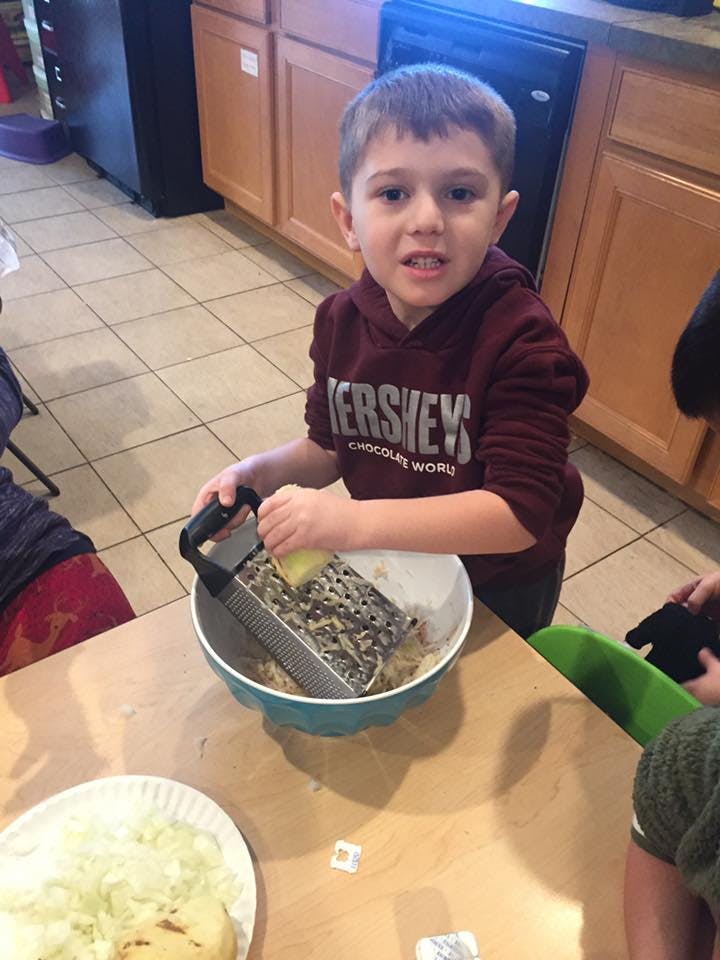 Child grating food into a bowl in a kitchen