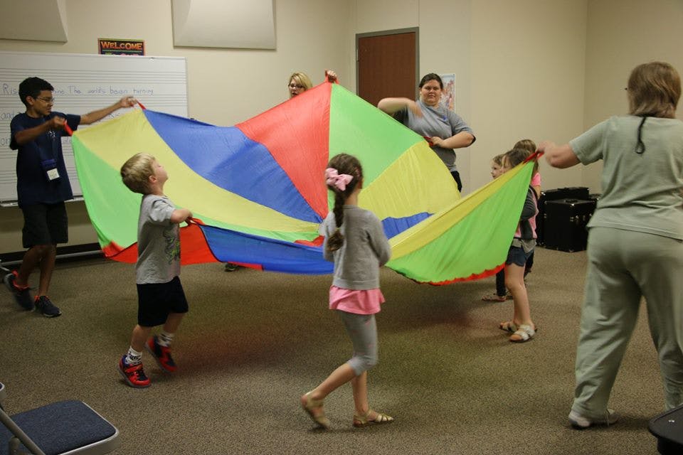 Children and adults playing with a colorful parachute