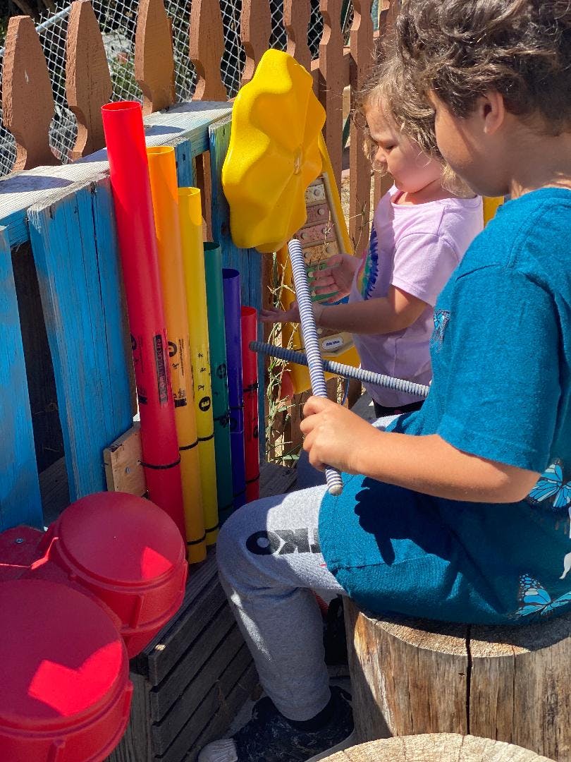 Two children playing with colorful outdoor musical instruments
