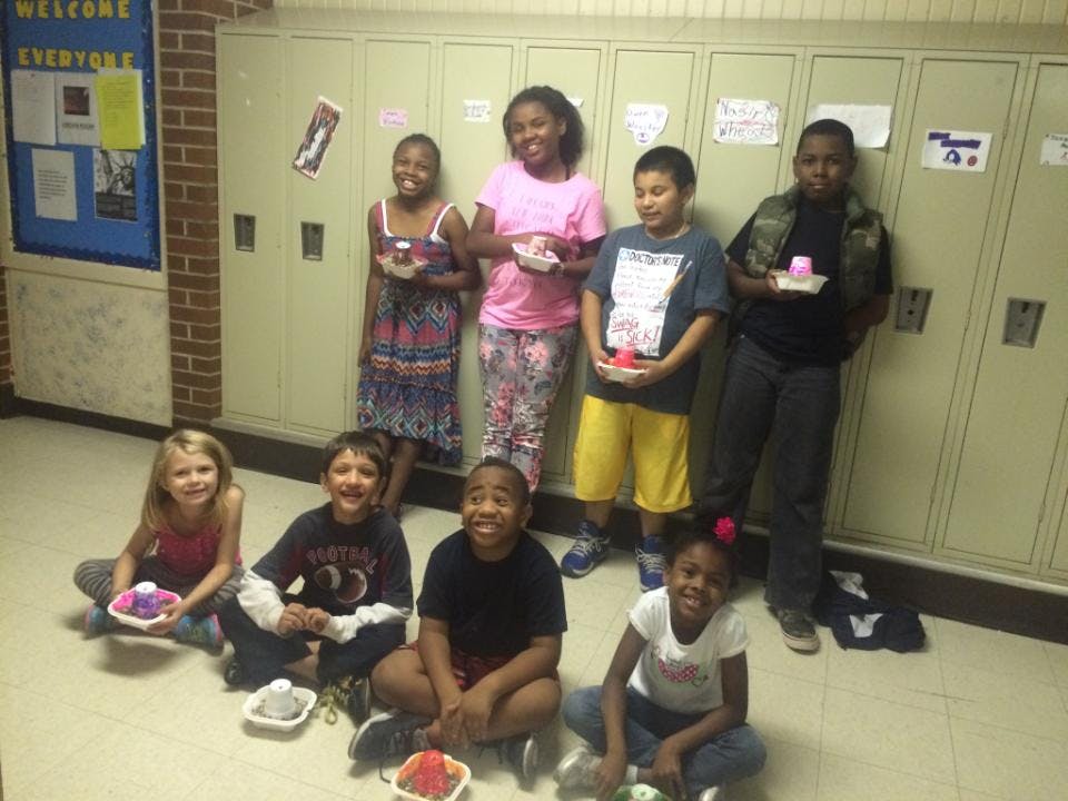 Group of children holding small containers, colorful objects