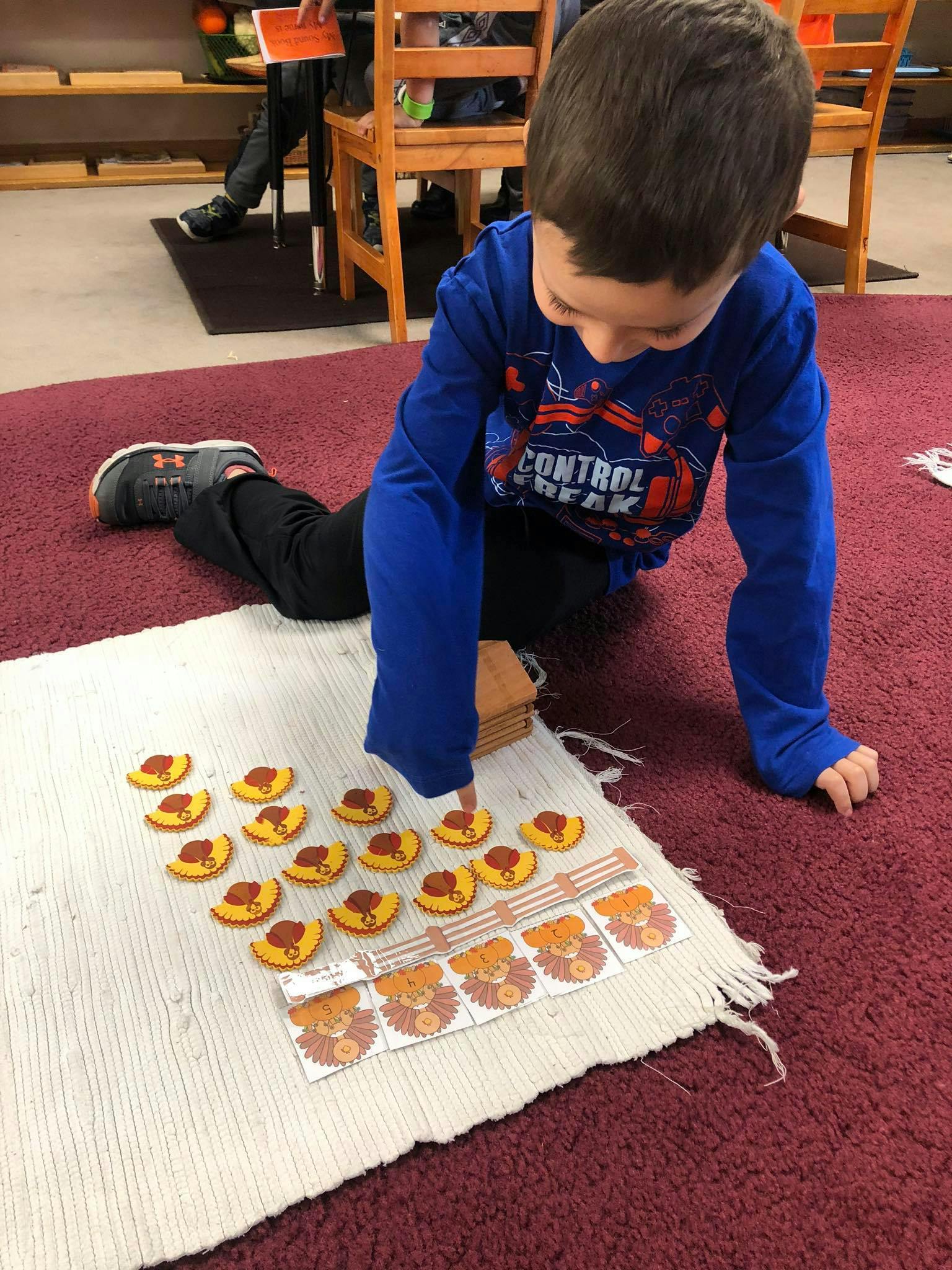 Child on floor playing with small yellow and red pieces on a white mat