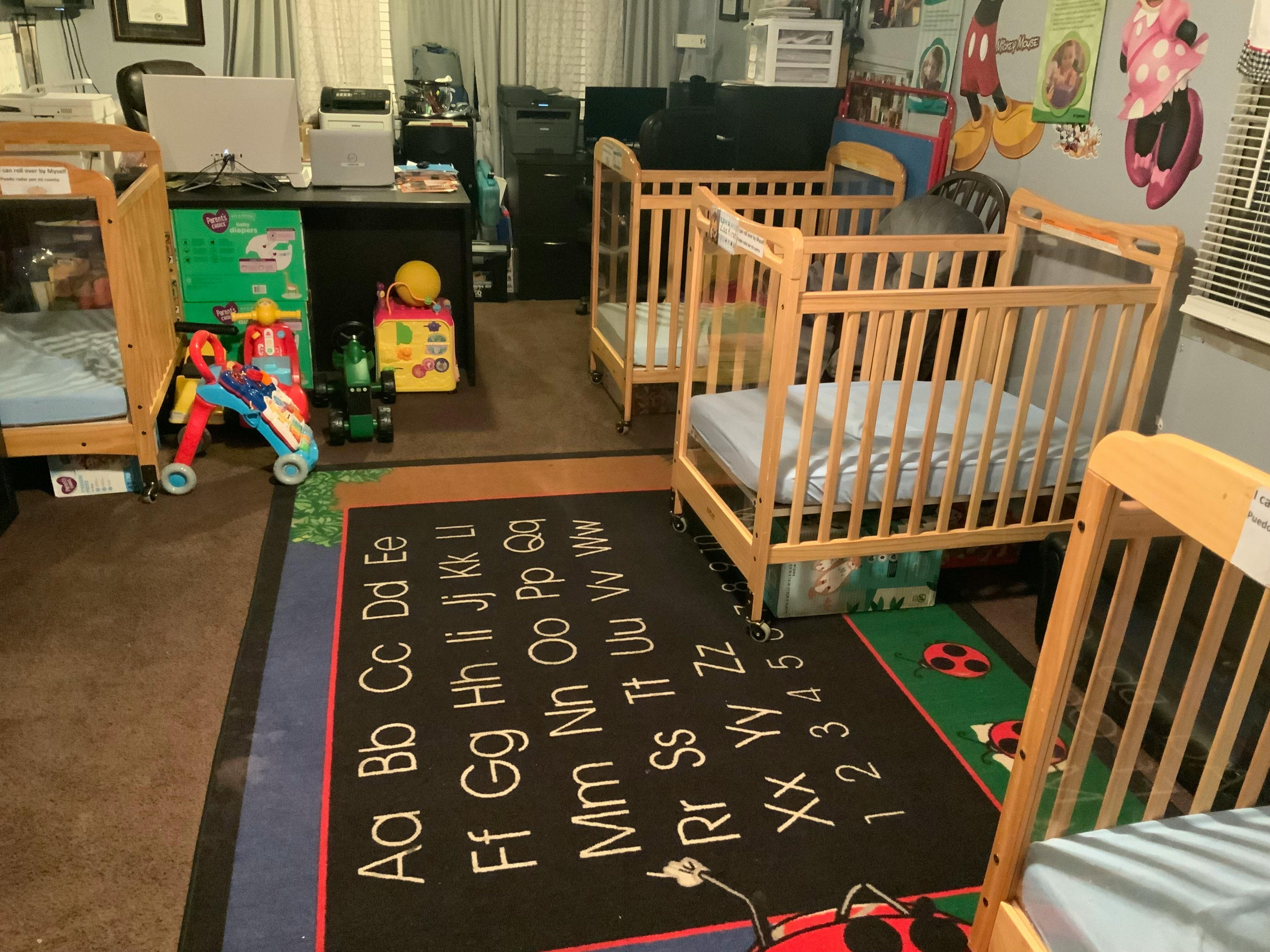 Room with multiple cribs and an alphabet rug