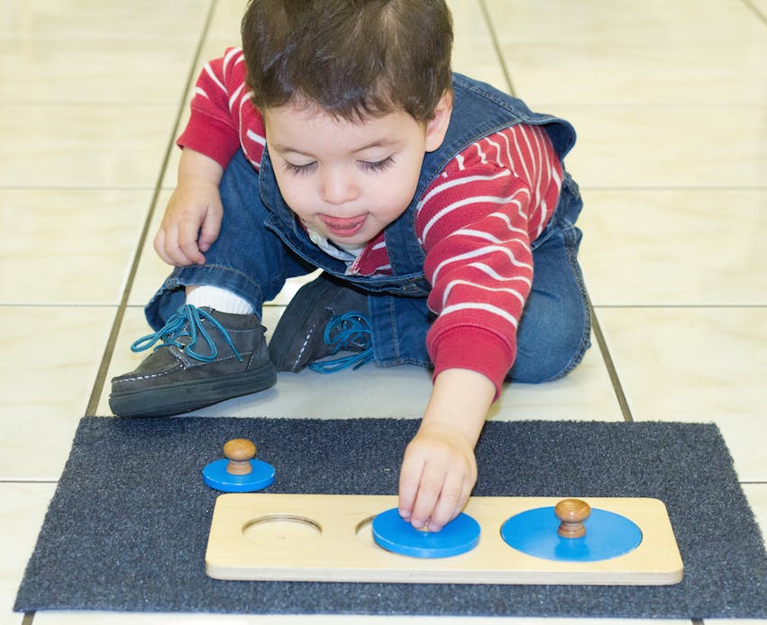 Child playing with a wooden puzzle on a mat