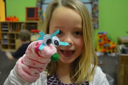 Child holding a sock puppet with googly eyes