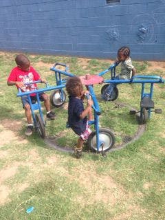 Three children on a playground merry-go-round