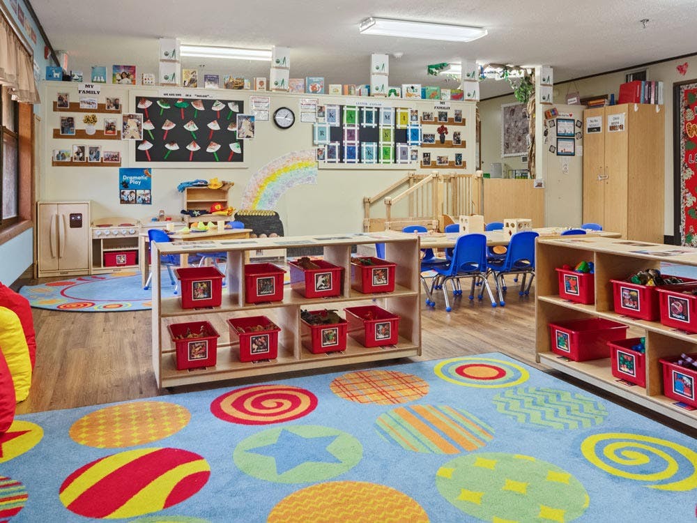 Colorful playroom or classroom with tables, chairs, and shelves of toys