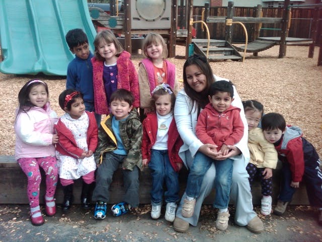 A group of children and an adult posing together on a playground