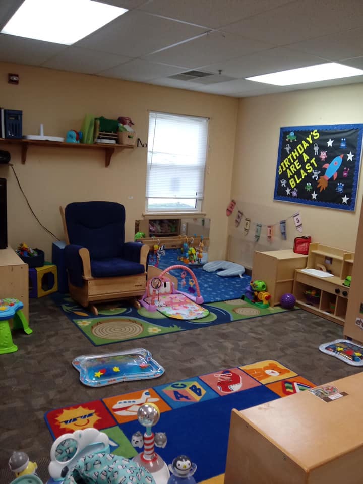Childcare room with a rocking chair, play mats, and toys