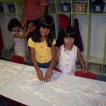 Two children standing at a table with white powder