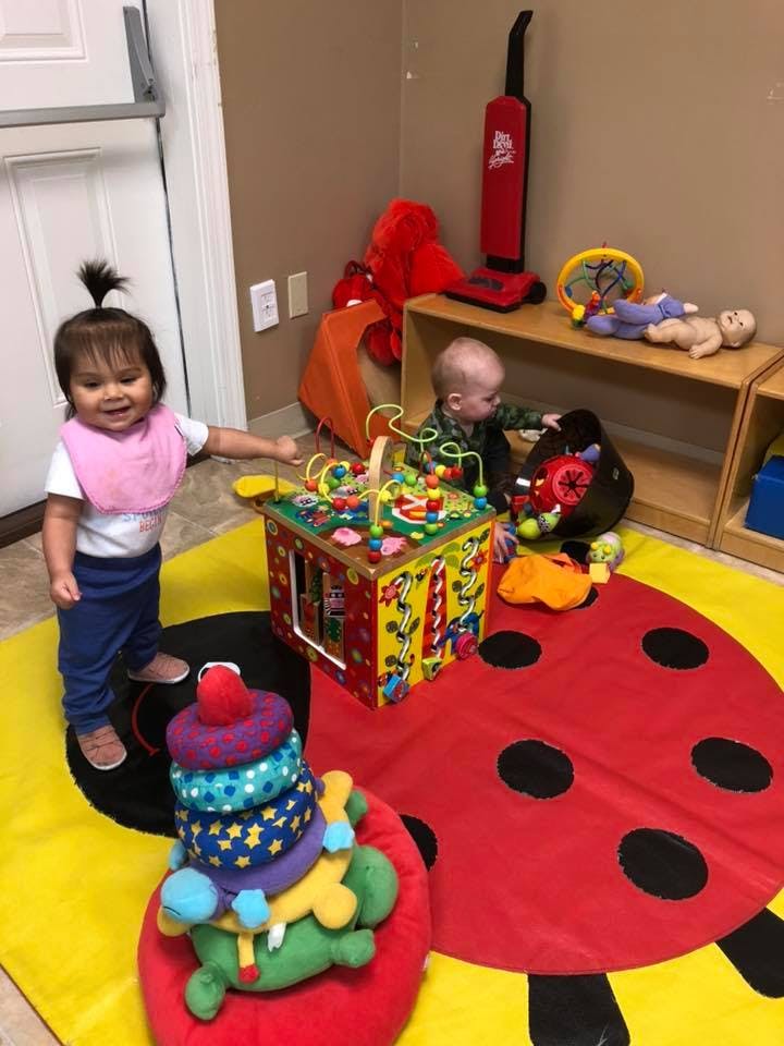 Two children playing with toys on a ladybug-shaped rug