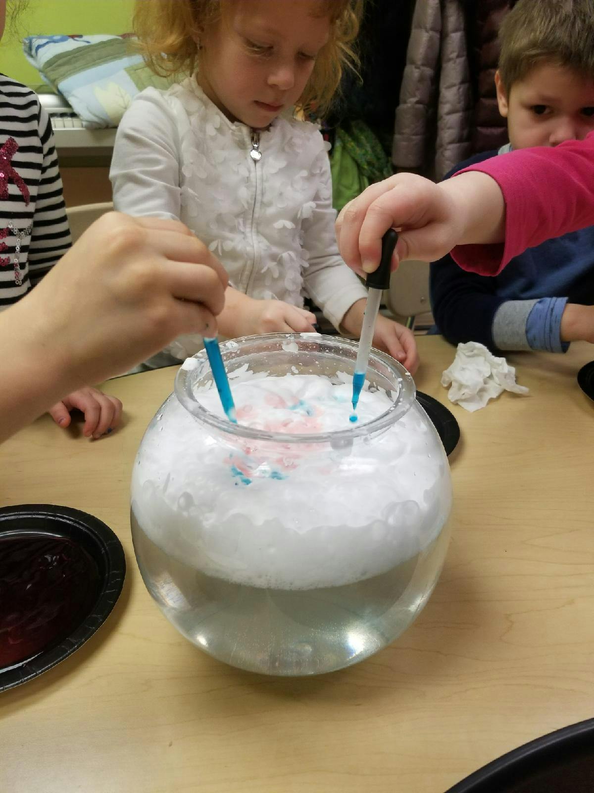 Children using droppers to add liquid to a bowl of foam