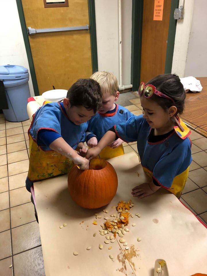 Three children carving a pumpkin