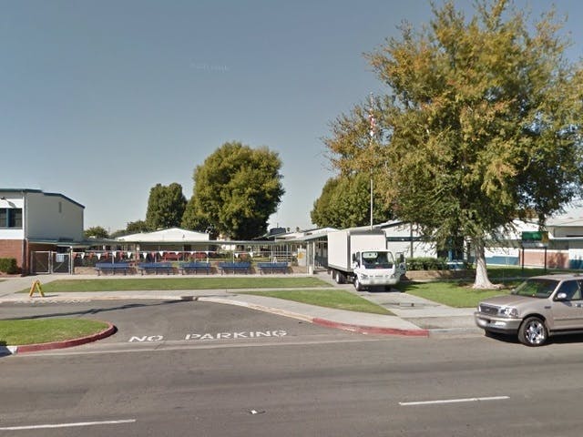 School building with a truck parked outside and a car on the street