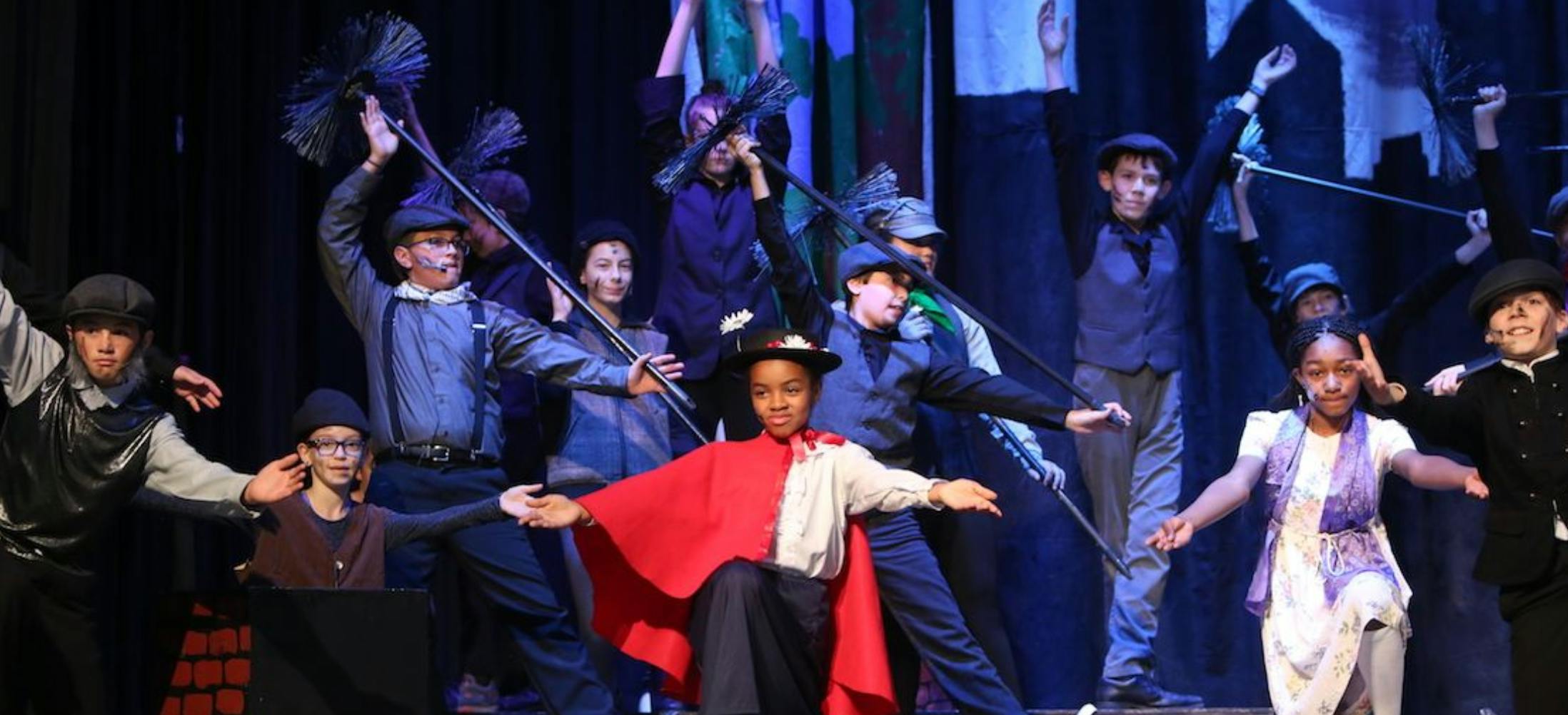 Children performing on stage in costumes