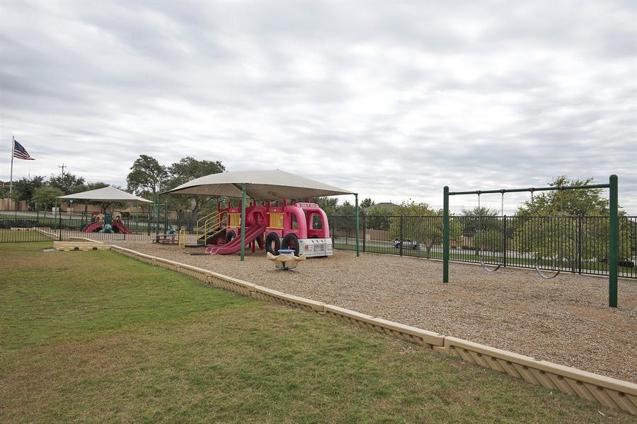 Empty playground with swings, slides, and a play structure under a shade structure
