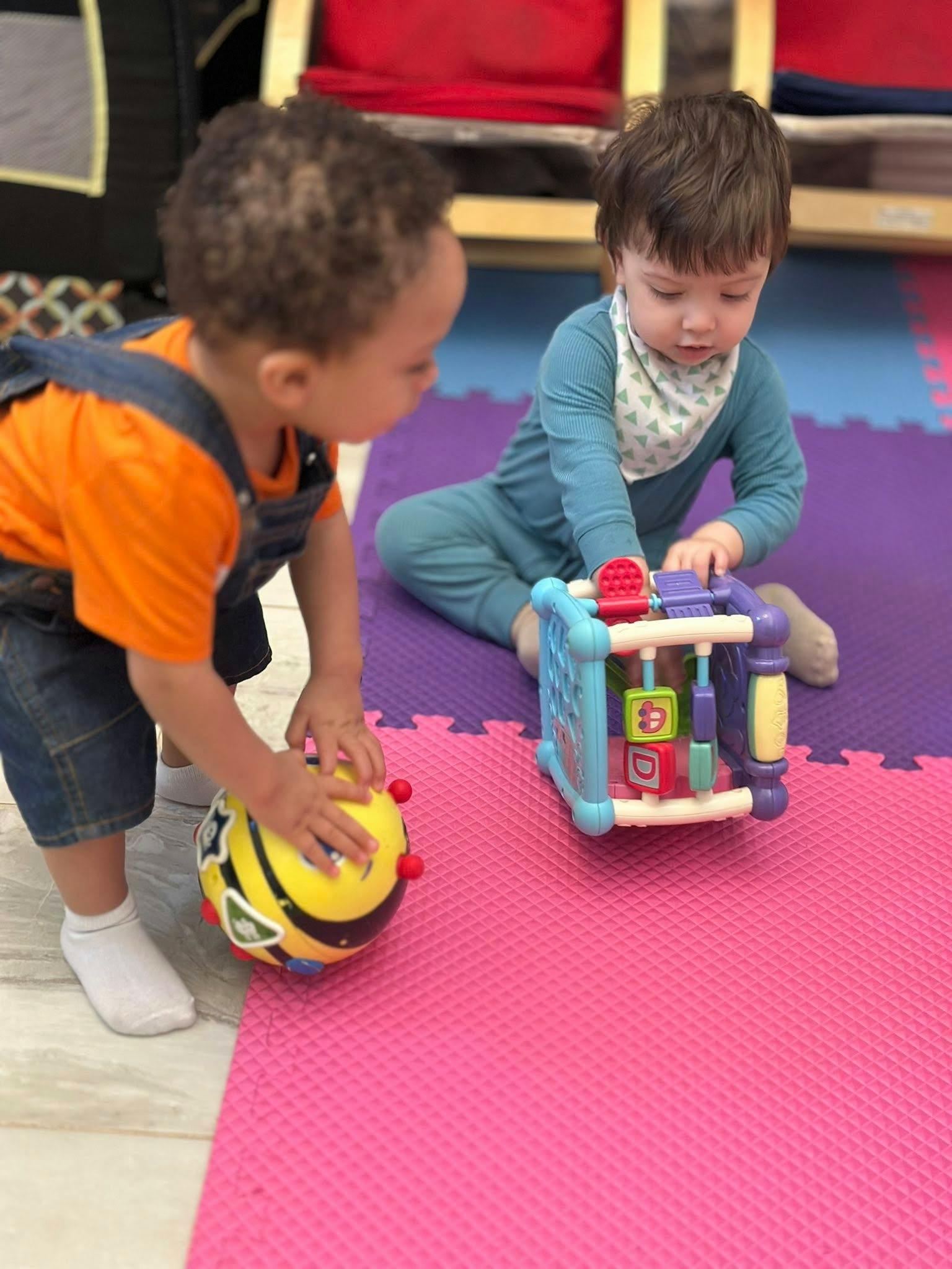 Two children playing with toys on a colorful mat