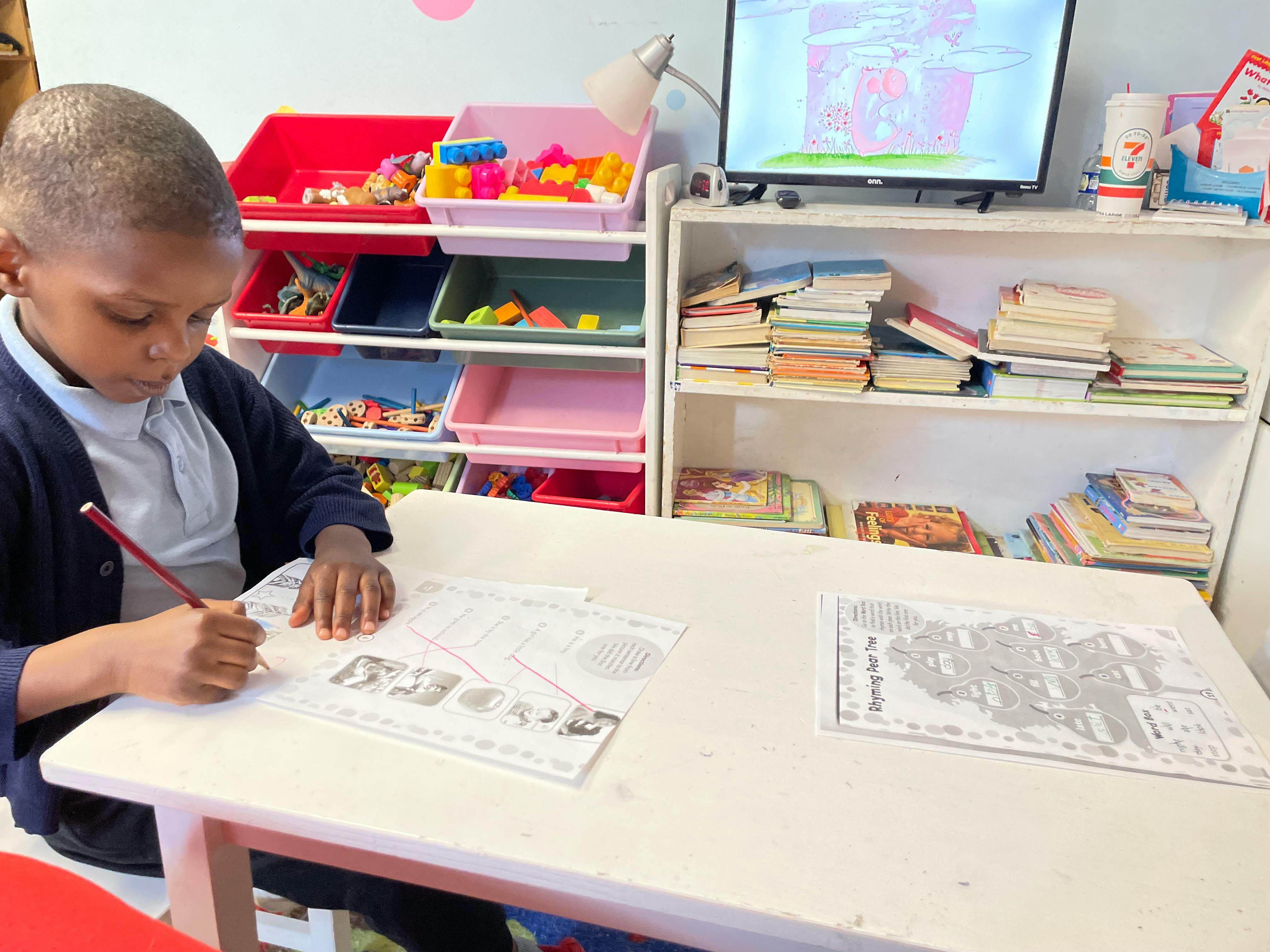 Child writing on paper at a desk in a classroom